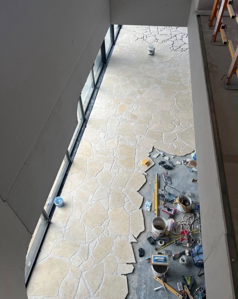 Crazy paving part-laid over bare concrete